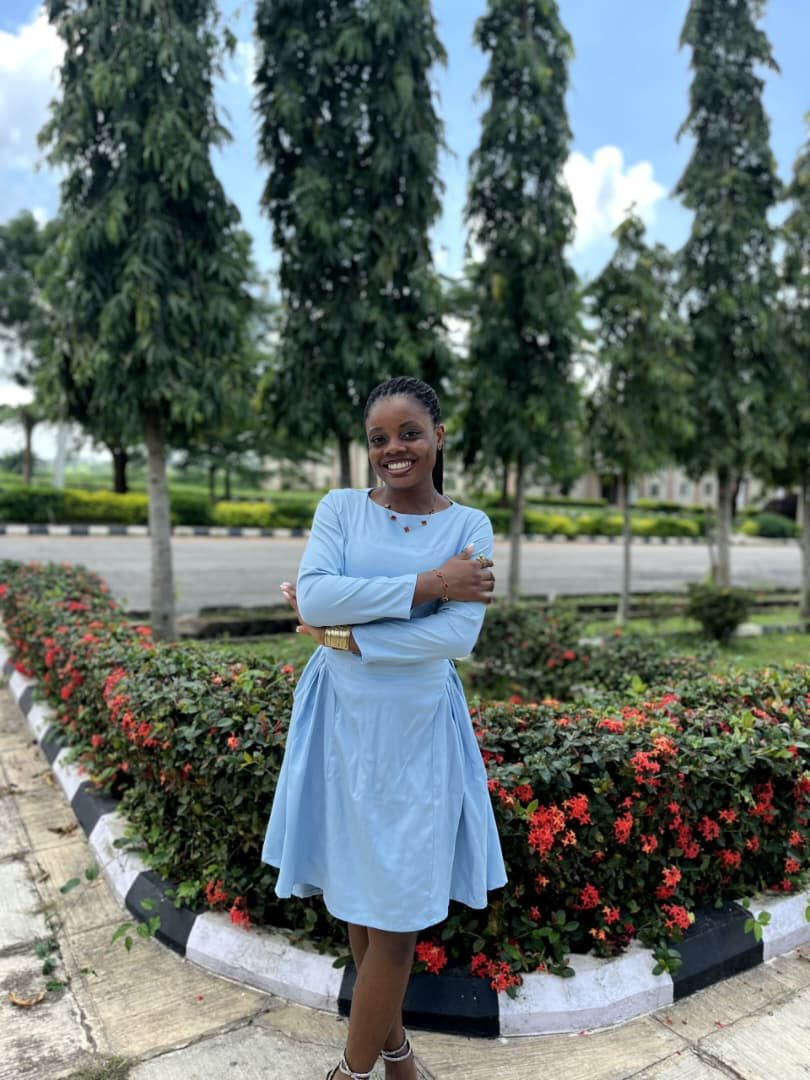 Neriah smiling in a light blue dress by the flowers